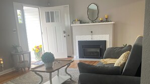 Una sala de estar con chimenea, un sofá, una mesa de centro y una alfombra.