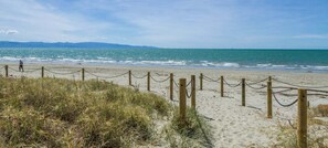 A beach with a wooden fence and a person walking. - Moana Sands - Beachside Apartment (Nelson)