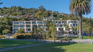 Et moderne hotel med flere etager, omgivet af grønt og en palme.