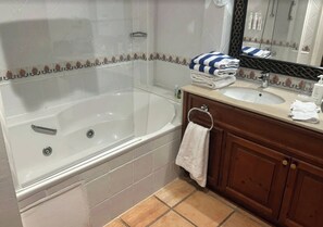 Ein Badezimmer mit einer Badewanne, einem Waschbecken, einem Spiegel und einem Handtuchhalter.
