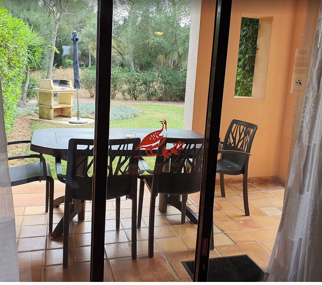 A patio area with a table and chairs, a small garden visible through a glass door, and a wall-mounted window.