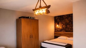 Un dormitorio con dos camas, un armario de madera, una pared de piedra y una lámpara colgante.