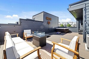 A rooftop terrace with outdoor seating, a glass-top table, and a sign reading 'NASH.' - Brand New | Close to Broadway | Rooftop Oasis | City Views | Private Hot Tub 🌃 (Nashville)