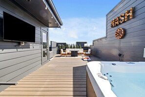 Eine moderne Außenterrasse mit Whirlpool, Flachbildfernseher und einem Schild mit der Aufschrift 'NASH'.