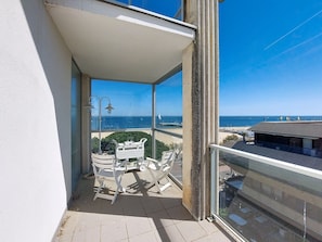 Ein Balkon mit Meerblick, ein Stuhl, ein Tisch und eine Lampe.