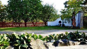 A paved pathway with a stone border, a wooden fence, and a white wall with a door and window. - Gästehaus Roensch (Frensdorf)