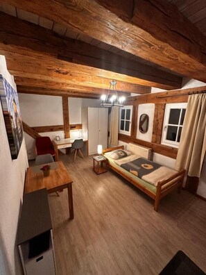 Una habitación acogedora con techo de madera, un sofá, una mesa y una silla.