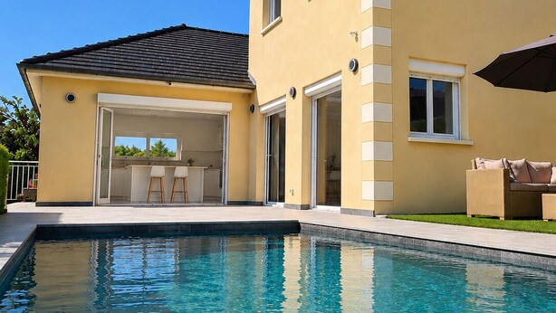 A two-story house with a swimming pool, a covered patio, and a dining area.
