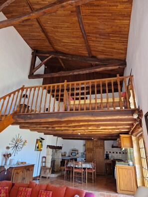 A rustic interior with a wooden balcony, a dining area, and a kitchen. - Country house, a little paradise (Castels et Bézenac)