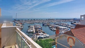 En lysthavn med mange både i havnen, en klar himmel og udsigt til havet.
