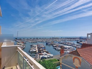 Ein Yachthafen mit zahlreichen Booten, ein klarer Himmel und Blick auf das Meer.