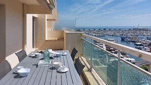 En balkon med et spisebord, der vender ud over en havn fyldt med både.