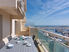 Ein Balkon mit Esstisch, der auf einen Hafen mit zahlreichen Booten blickt.