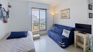 Et værelse med seng, sofa, fjernsyn og balkon med udsigt.