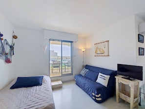 Ein Zimmer mit Bett, einer Couch, einem Fernseher und einem Balkon mit Blick.