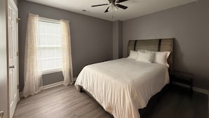 A bedroom with a bed, a ceiling fan, a window with curtains, and a door. - Quiet Fully Furnished Comfy Home with Fast WiFi for Professionals in RTP/Durham (Durham)