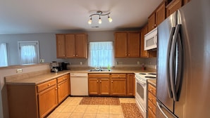 A kitchen with wooden cabinets, a stainless steel refrigerator, a dishwasher, and a stove. - Quiet Fully Furnished Comfy Home with Fast WiFi for Professionals in RTP/Durham (Durham)