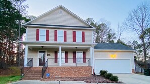 A two-story house with a front porch, a garage, and a well-maintained lawn. - Quiet Fully Furnished Comfy Home with Fast WiFi for Professionals in RTP/Durham (Durham)