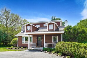 A two-story house with a front porch, a chimney, and a well-maintained garden.