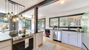 A modern kitchen with a central island, stainless steel appliances, and hanging pendant lights. - Linn Lodge | Fire Pit, 5+ Night Stays Include Golf Cart | Sleeps 10 (Lake Geneva)