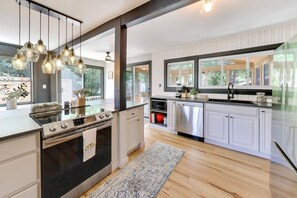 Una cocina moderna con una isla central, electrodomésticos de acero inoxidable e iluminación colgante.