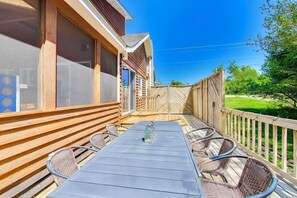 Eine überdachte Terrasse mit Tisch und Stühlen, Holzgeländern und Blick ins umliegende Grün.