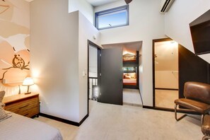Ein Schlafzimmer mit einem Bett, einem Nachttisch, einer Lampe, einem Sessel, einem Kleiderschrank und einem durch eine offene Tür einsehbarer Badezimmer.