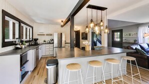 A modern kitchen with a central island, bar stools, and pendant lighting. - Linn Lodge | Fire Pit, 5+ Night Stays Include Golf Cart | Sleeps 10 (Lake Geneva)