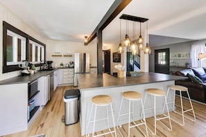 Una cocina moderna con una isla central, taburetes de bar e iluminación colgante.