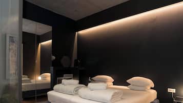 Un dormitorio moderno con una cama grande, mesitas de noche, un espejo y una lámpara fijada a la pared.