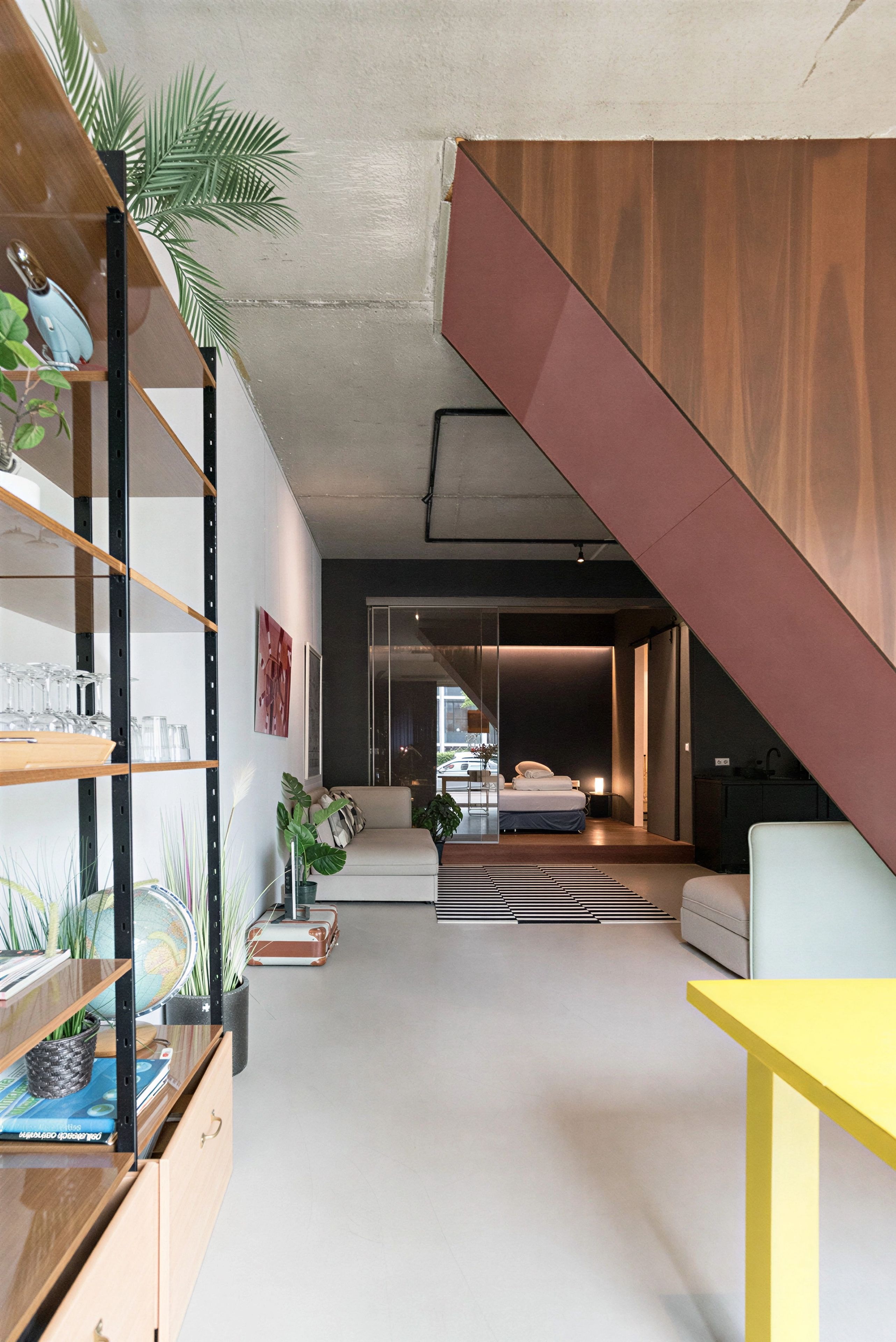 Un interior moderno con una escalera, un sofá, una mesa de comedor y una zona de cocina.