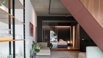 Un interior moderno con una escalera, un sofá, una mesa de comedor y una zona de cocina.