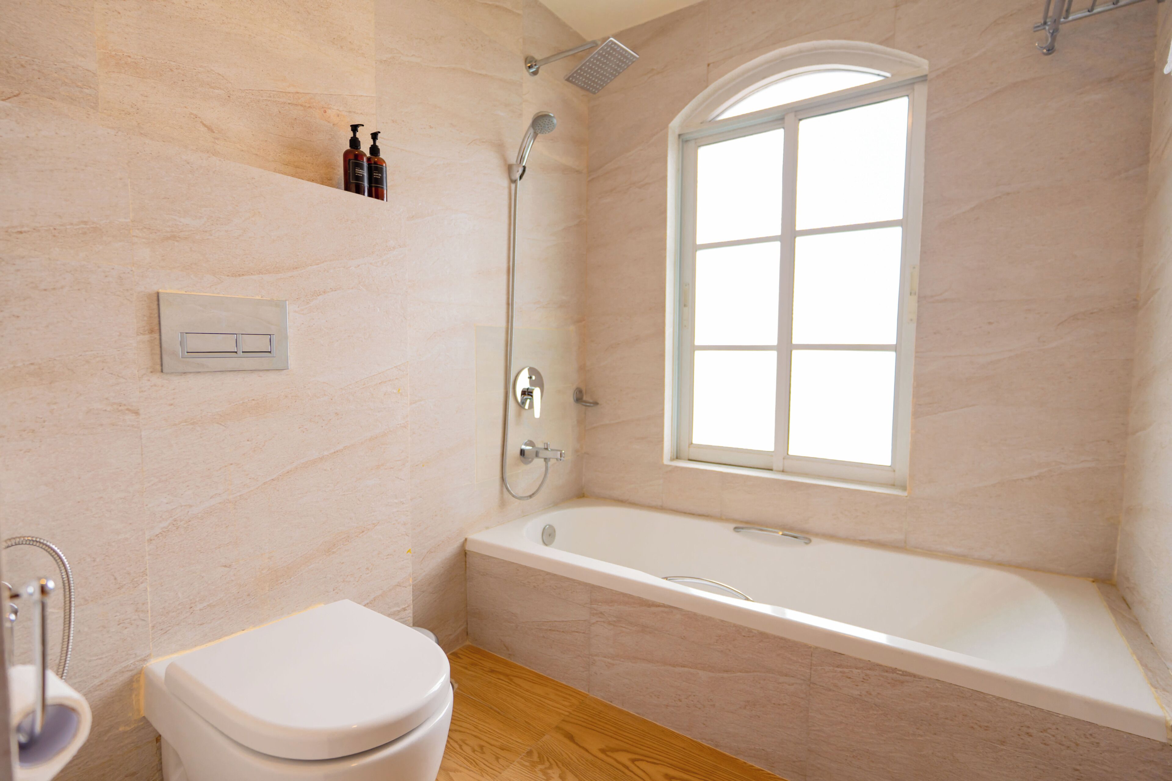 Un baño con una bañera blanca, inodoro, ducha y ventana.