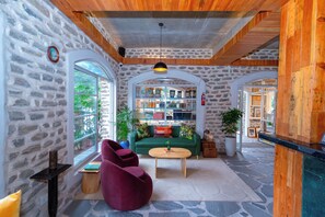 Un interior acogedor con pared de piedra, techo de madera y sofá verde.