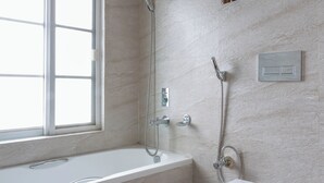 A modern bathroom with a bathtub, toilet, shower, and a window. - Nomad Pokhara Hotel  (Pokhara)