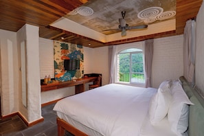 Un dormitorio con una cama grande, un ventilador de techo, una ventana con cortinas y una pared con un mural.