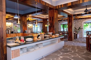 A buffet area with a stone floor, wooden beams, and hanging pendant lights. - Nomad Pokhara Hotel  (Pokhara)