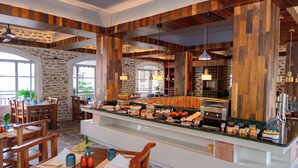 A breakfast buffet with a variety of food options, wooden accents, and a stone wall. - Nomad Pokhara Hotel  (Pokhara)