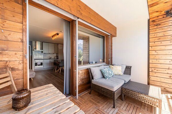 A wooden exterior with a sliding glass door leading to a kitchen and a seating area with a sofa and table.
