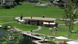 A lakeside hotel with a central building, a dock, and a grassy area with umbrellas.