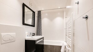 A modern bathroom with a white sink, black cabinet, and a bathtub.