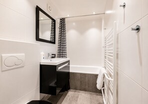 A modern bathroom with a white sink, black cabinet, and a bathtub.
