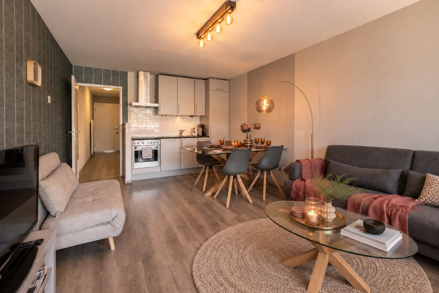 Ein modernes Wohnzimmer mit einer Couch, einem Glastisch und einem Essbereich mit Stühlen und einem Tisch.