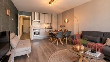 Een moderne woonkamer met een bank, een glazen salontafel en een eethoek met stoelen en een tafel.