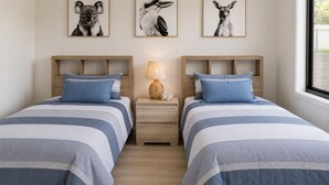 A bedroom with two beds, a nightstand with a lamp, and three framed animal pictures on the wall. - Wake to Ocean Views & Wildlife at Ohana Ocean Breeze (Penneshaw)