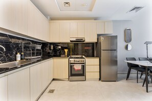 Eine moderne Küche mit hellen Holzschränken, einem Edelstahlkühlschrank, einem eingebauten Backofen und einem Essbereich mit Tisch und Stühlen.