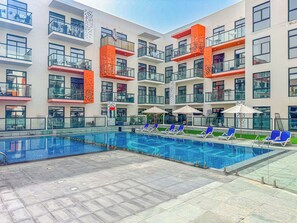 Ein modernes Hotel mit Schwimmbad, mehreren Balkonen und Außenbereichen zum Sitzen.
