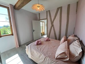 Une chambre à coucher avec un lit, une fenêtre et une porte donnant sur une autre pièce.