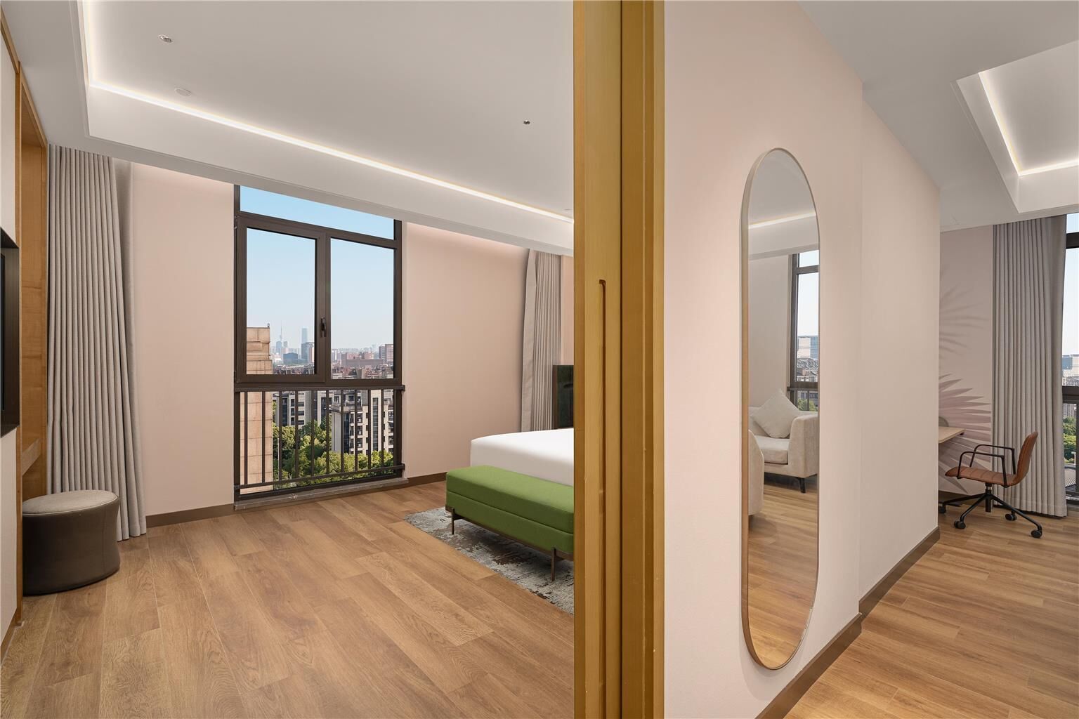 A modern hotel room with a large window, a bed, a desk, and a chair.