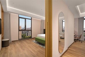 Et moderne hotelværelse med et stort vindue, en seng, et skrivebord og en stol.